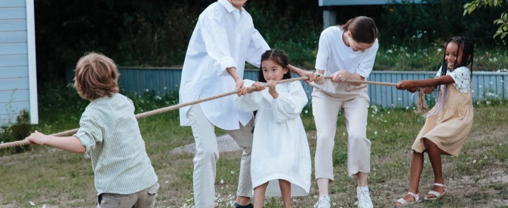 Family playing tug of war in backyard, showcasing teamwork and joy.