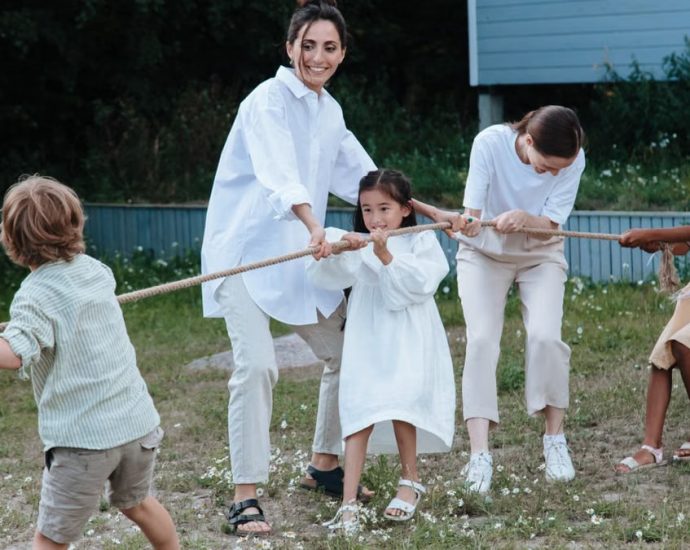 Family playing tug of war in backyard, showcasing teamwork and joy.