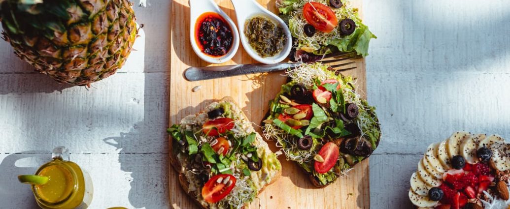 Top view of a vibrant and healthy brunch spread with sandwiches, fruits, and juices on a wooden table.
