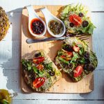 Top view of a vibrant and healthy brunch spread with sandwiches, fruits, and juices on a wooden table.