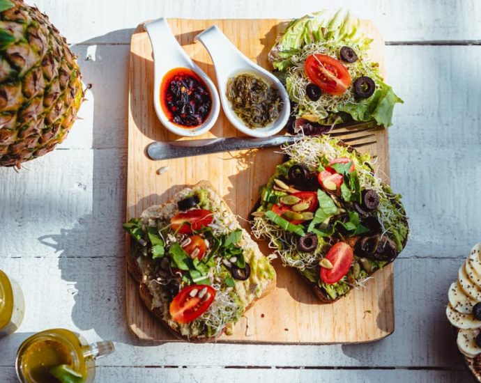 Top view of a vibrant and healthy brunch spread with sandwiches, fruits, and juices on a wooden table.